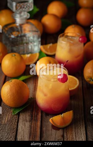 Tequila-Cocktail bei Sonnenaufgang, in leuchtenden Farben von Orangensaft und Grenadine, garniert mit einer Maraschino-Kirsche. Stockfoto