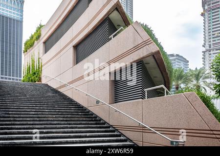 Abstrakte Treppen, abstrakte Treppen in der Stadt. Eine moderne Treppe mit breiten, glatten Betonstufen und eleganten Handläufen aus Edelstahl. Modernes Stadtviertel Stockfoto