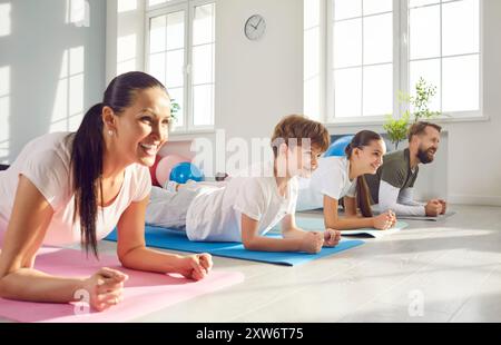 Familie, die Plank Sport Bewegung macht, liegt auf Yogamatte auf dem Boden im Wohnzimmer zu Hause. Stockfoto