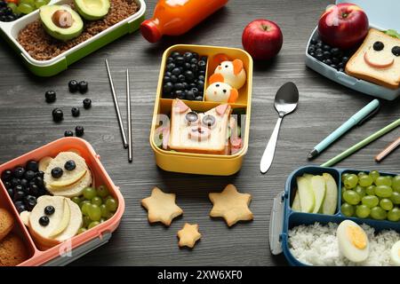 Lunchboxen mit verschiedenen Snacks, einer Flasche Saft und Besteck auf Holztisch, über dem Blick Stockfoto