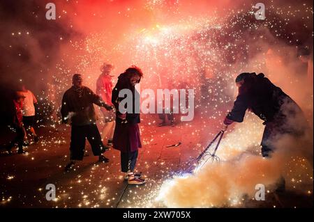 Barcelona, Spanien. August 2024. 17. August 2024, Barcelona, Spanien: Die Teufel nehmen an einem Korrefoc inmitten der Pyrotechnik während der Feier des Sant Roc Festivals in Barcelona Teil. Correfocs, eine alte katalanische Tradition, bei der Menschen, die als Teufel gekleidet sind, Feuerwerkskörper und Fackeln in die Luft jagen, nehmen jeden August an den Feierlichkeiten für das Sant Roc Festival im gotischen Viertel von Barcelona Teil. Quelle: Jordi Boixareu/Alamy Live News Stockfoto