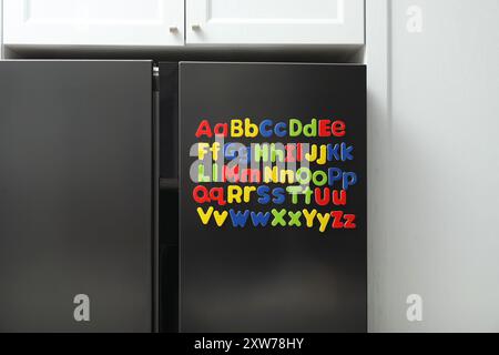 Alphabetische Reihenfolge. Viele helle magnetische Buchstaben auf dem Kühlschrank in Innenräumen Stockfoto