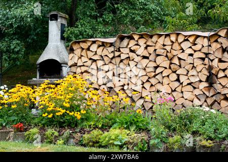 Kamin im Garten und Holz für den Winter gelagert, gestapelte Baumstämme Stockfoto