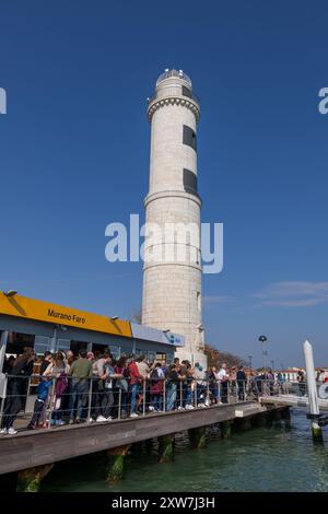 Murano, Veneto, Italien - 23. März 2024 - Leuchtturm Faro di Murano und Angel von Menschen an der Fährplattform an der Lagune von Venedig warten auf WA Stockfoto