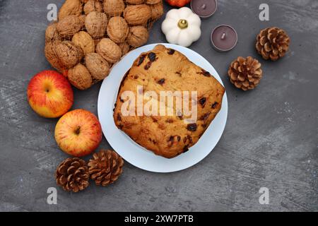 Rosinenfruchtkuchen Dessert traditionelles Gebäck getrocknete Früchte, Nüsse, Äpfel, Kegel und Kerzen auf dunkelgrauem Hintergrund mit Kopierraum. Ideen für Herbstmenüs. Stockfoto