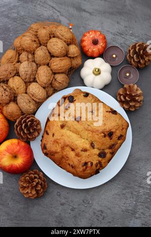 Rosinenfruchtkuchen Dessert traditionelles Gebäck getrocknete Früchte, Nüsse, Äpfel, Kegel und Kerzen auf dunkelgrauem Hintergrund mit Kopierraum. Ideen für Herbstmenüs. Stockfoto