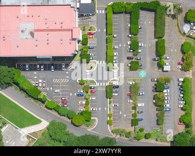 Großer Parkplatz mit grünen Büschen neben dem Bürogebäude aus der Luft von oben Stockfoto