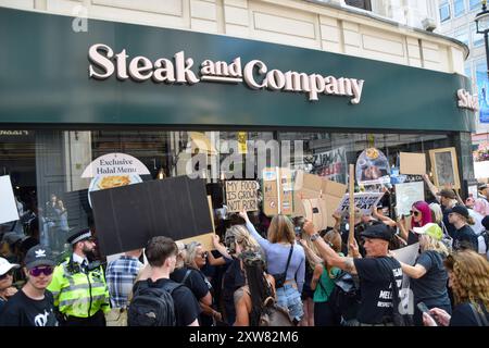 London, Großbritannien. August 2024. Demonstranten halten Schilder vor einem Steakrestaurant hoch, während Tausende von Tierschützern am National Animal Rights March im Zentrum Londons teilnehmen. Der jährliche Protest hebt das Leiden und den Tod von Milliarden von Tieren in allen Bereichen menschlichen Handelns hervor, kämpft für die Tierbefreiung und für ein Ende der Tierausbeutung und fördert Veganismus und einen grausamen Lebensstil. Quelle: Vuk Valcic/Alamy Live News Stockfoto