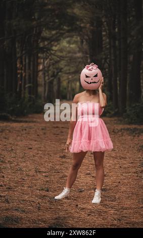 Frau posiert in rosa Jack o Laterne Kostüm mit dunklem Wald im Hintergrund Stockfoto