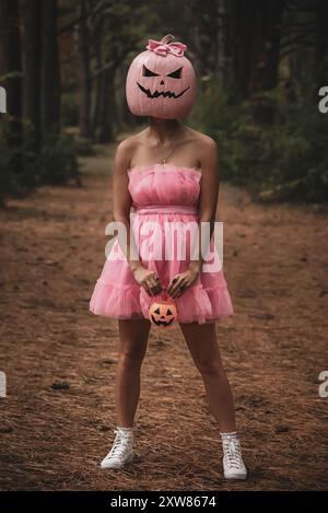 Frau posiert in rosa Jack o Laterne Kostüm mit dunklem Wald im Hintergrund Stockfoto