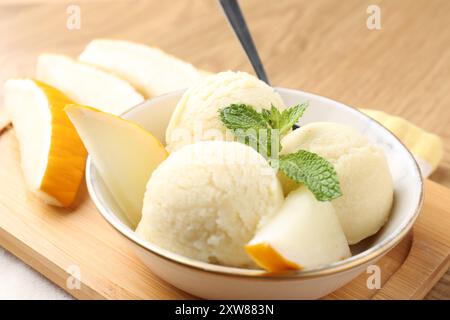 Löffel leckeres Melonensorbet mit frischem Obst und Minze in einer Schüssel auf dem Tisch, Nahaufnahme Stockfoto