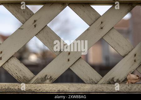 Bei Sonnenuntergang beleuchteter Gitterzaun mit abblätternder weißer Farbe - Nahperspektive zeigt Textur und Muster. Aufgenommen in Toronto, Kanada. Stockfoto