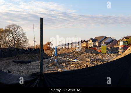 Goldene Stunde auf einer Baustelle in Vorstädten - Erdhügel und Baumaterialien im Vordergrund. Aufgenommen in Toronto, Kanada. Stockfoto