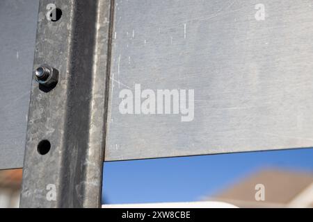 Rückansicht eines Straßenschilds aus Metall mit verschraubten Verbindungen und verwitterter Oberfläche – klarer blauer Himmel im Hintergrund. Aufgenommen in Toronto, Kanada. Stockfoto