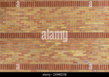 Warme Ziegelwand mit verschiedenen Rot- und Orangetönen, horizontale graue Zementlinien. Aufgenommen in Toronto, Kanada. Stockfoto