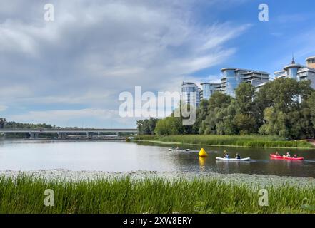 Ukraine, Kiew - 16. August 2024: Die Menschen fahren an einem sonnigen Sommertag auf Schlauchbooten und Kajaks entlang des Stadtflusses. Wochenende in der Stadt Stockfoto