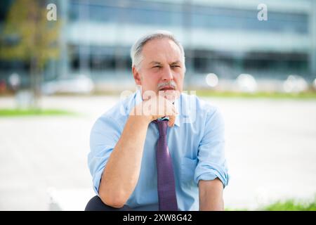 Nachdenklicher und nachdenklicher Senior-Geschäftsmann im Freien Stockfoto