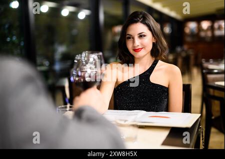 Glückliches Paar genießt ein romantisches Abendessen in einem schicken Restaurant, das in Liebe und Verbundenheit eingetaucht ist. Sie lächeln und genießen das elegante Ambiente und das feine Abendessen Stockfoto