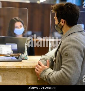 Kunde, der an der Hotelrezeption eincheckt, trägt Masken zum Schutz vor covid 19-Coronavirus-Pandemie Stockfoto