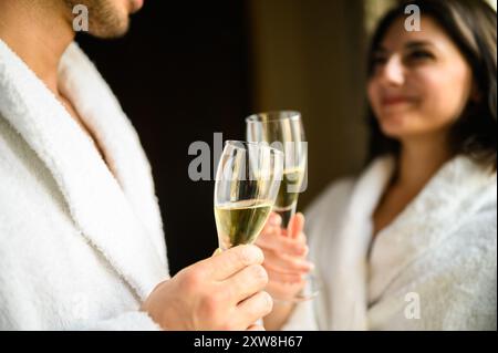 Fröhliches Paar im Bademantel, das Sektgläser toast Stockfoto