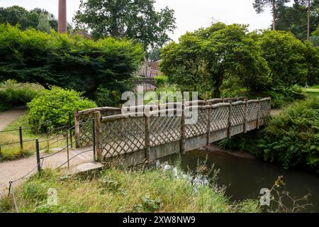 Die Gärten in Quarry Bank, Styal, Cheshire, England. Eine hölzerne Brücke über den Fluss Bollin. Stockfoto