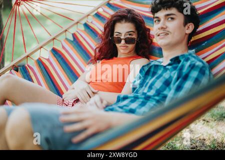 Zwei Freunde, die sich an einem sonnigen Tag in einer bunten Hängematte im Freien entspannen Stockfoto