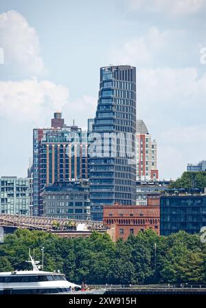 Riesige segelförmige Olympia DUMBO Eigentumswohnungen erhebt sich hinter dem Wahrzeichen Eagle Warehouse & Storage in dieser Aussicht von einer East River Fähre. Stockfoto