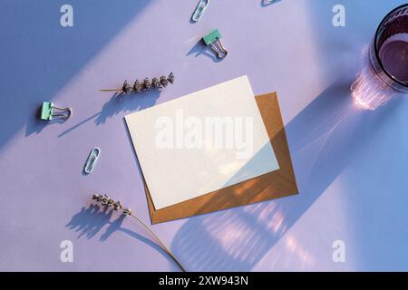 Modernes Sommer-Schreibwaren-Stillleben. Ein Glas Wasser mit langem Schatten, Lavendelblume auf violettem Hintergrund. Leeres Visitenkartenmodell. Draufsicht, fl Stockfoto