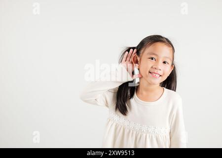 Portrait Asiatisches kleines Kind lächelnd hörend hörend Tratsch mit Aufmerksamkeit mit der Hand Stockfoto