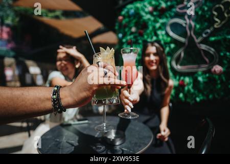 Multikulturelle Geschäftsleute genießen Drinks und jubeln den Erfolg in einem Café im Freien an Stockfoto