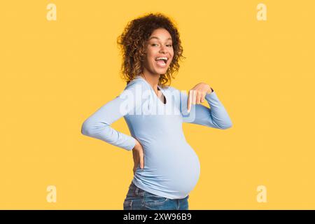 Überfreute schwarze schwangere Frau, die auf ihren Bauch zeigt Stockfoto