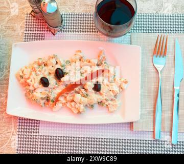 Olivier-Salat aus gekochtem Gemüse, garniert mit schwarzen Oliven Stockfoto