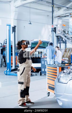 Zertifizierter Mechaniker in der Werkstatt mit VR-Brillen und Augmented Reality-Hologramm zur Visualisierung von Autoteilen, um diese zu reparieren. BIPOC-Frau verwendet AR-Technologie, während sie an gebrochenen Fahrzeugbremsen arbeitet Stockfoto