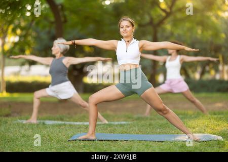 Junge weibliche Yogalehrerin, die Gruppenunterricht im Freien führt Stockfoto