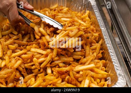 Partyschale mit Pommes frites. Zange, die Pommes frites schnappt. Stockfoto