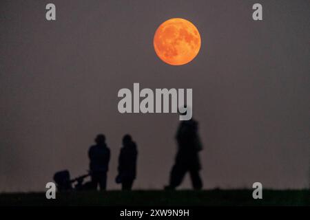 London, Großbritannien. August 2024. Wetter in Großbritannien: Sturgeon Blue Supermoon (Wachs-Gibbous) steigt mit 99 % am Sonntagabend um 21:02 über Parliament Hill im Nordwesten Londons. Traditionell als Sturgeon Moon bezeichnet, weil der Riesenstörer der Großen Seen und des Lake Champlain in in dieser Sommerhälfte am leichtesten gefangen wurde“, so der Almanach des Almanachs. Guy Corbishley/Alamy Live News Stockfoto