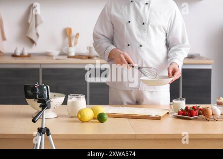 Männlicher Koch mit Teig und Obst, die Kochvideo in der Küche aufzeichnen Stockfoto