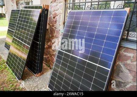 Stapel neuer Solarpaneele mit Schutzpappe, bereit für die Installation. Erneuerbare Energien, nachhaltige Wohnungsverbesserung und umweltfreundliche Investitionen in die Infrastruktur von Wohneigentum. Stockfoto