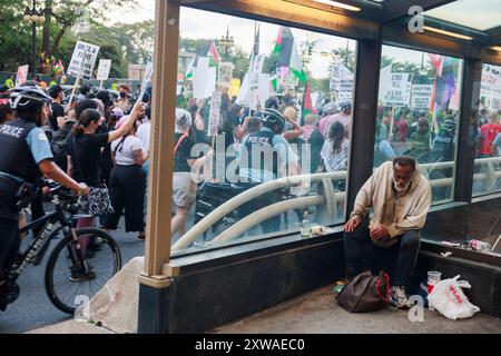 Chicago, USA. August 2024. CHICAGO, ILLINOIS – 18. AUGUST: Ein unbewohnter Mann sitzt in der Nähe von Pro-Palästina-Demonstranten, die am 18. August 2024 in Chicago, Illinois, vor der Demokratischen Nationalkonvention marschieren. Die Konferenz findet vom 19. Bis 22. August statt. Quelle: Jeremy Hogan/Alamy Live News Stockfoto