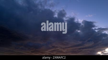 Tropischer Sonnenuntergang. Wunderschöner Sonnenuntergangshimmel mit Wolken. Orangefarbener Sonnenuntergang, dunkle Wolken am Himmel. Hintergrund der dunklen Wolken vor dem Sturm. Dramatische Wolken Stockfoto