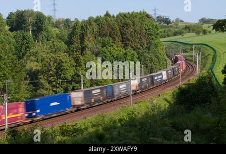 Freightliner intermodaler Containerzug, der durch die Landschaft von Cumbria auf der Hauptstrecke der Westküste bei Bessy Ghyll fährt Stockfoto