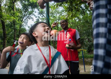 (240819) -- WUHAN, 19. August 2024 (Xinhua) -- Lugazo Abubakar Lugazo (hinten) interagiert mit Kindern während einer Freiwilligentätigkeit in Wuhan, Zentralchinas Provinz Hubei, 19. Mai 2024. Lugazo Abubakar Lugazo, ein 30-jähriger Tansania, promoviert derzeit an der Central China Normal University (CCNU) in Wuhan. Neben seinem Studium ist er auch Leiter eines Freiwilligen-Service-Teams, das sich aus internationalen Studenten zusammensetzt. Lugazos Zuneigung für China begann während seines Bachelorstudiums in Tansania. Angeregt von einem chinesischen Lehrer an einem Konfuzius-Institut, begann Lugazo seine Karriere Stockfoto