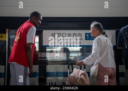 (240819) -- WUHAN, 19. August 2024 (Xinhua) -- Lugazo Abubakar Lugazo (L) bietet Hilfe für einen Passagier an einer U-Bahn-Station in Wuhan, zentralchinesische Provinz Hubei, 18. August 2024. Lugazo Abubakar Lugazo, ein 30-jähriger Tansania, promoviert derzeit an der Central China Normal University (CCNU) in Wuhan. Neben seinem Studium ist er auch Leiter eines Freiwilligen-Service-Teams, das sich aus internationalen Studenten zusammensetzt. Lugazos Zuneigung für China begann während seines Bachelorstudiums in Tansania. Ermutigt von einem chinesischen Lehrer an einem Konfuzius-Institut, begann Lugazo seine Reise o Stockfoto