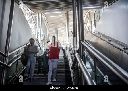 (240819) -- WUHAN, 19. August 2024 (Xinhua) -- Lugazo Abubakar Lugazo (R) hilft einem Passagier an einer U-Bahn-Station in Wuhan, Zentralchinas Provinz Hubei, 18. August 2024. Lugazo Abubakar Lugazo, ein 30-jähriger Tansania, promoviert derzeit an der Central China Normal University (CCNU) in Wuhan. Neben seinem Studium ist er auch Leiter eines Freiwilligen-Service-Teams, das sich aus internationalen Studenten zusammensetzt. Lugazos Zuneigung für China begann während seines Bachelorstudiums in Tansania. Ermutigt von einem chinesischen Lehrer an einem Konfuzius-Institut, begann Lugazo seine Reise o Stockfoto