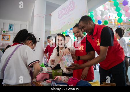 (240819) -- WUHAN, 19. August 2024 (Xinhua) -- Lugazo Abubakar Lugazo (1. R) schließt sich einem Wohltätigkeitsbasar in Wuhan, Zentralchinas Provinz Hubei, am 31. Mai 2024 an. Lugazo Abubakar Lugazo, ein 30-jähriger Tansania, promoviert derzeit an der Central China Normal University (CCNU) in Wuhan. Neben seinem Studium ist er auch Leiter eines Freiwilligen-Service-Teams, das sich aus internationalen Studenten zusammensetzt. Lugazos Zuneigung für China begann während seines Bachelorstudiums in Tansania. Angeregt von einem chinesischen Lehrer an einem Konfuzius-Institut, begann Lugazo seine Reise, Chinesisch an C zu lernen Stockfoto