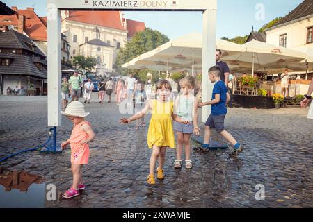 Kazimierz Dolny, Polen - 20. August 2022: Kinder laufen durch den Wasservorhang auf dem Hauptplatz von Kazimierz Dolny Stockfoto