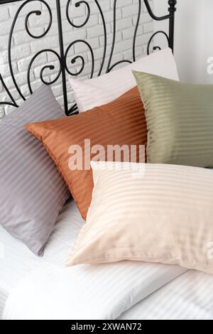 Gestreifte Kissen auf einem Bett mit Kopfteil aus schwarzem Metall Stockfoto