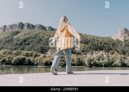 Frau im gelben Regenmantel, die auf einem Holzsteg läuft Stockfoto