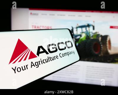 Mobiltelefon mit Logo des amerikanischen Landmaschinenunternehmens AGCO Corporation vor der Website. Fokussieren Sie sich auf die linke Mitte des Telefondisplays. Stockfoto