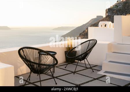 Zwei schwarze Korbstühle auf einer Terrasse in Santorin mit Blick auf das Meer Stockfoto